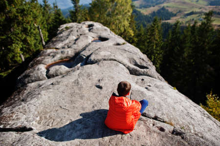 Boy on top of mountain. Children hiking on beautiful day in mountains, resting on rock and admire amazing view peaks. Active family vacation leisure with kids.Outdoor fun and healthy activity.の写真素材