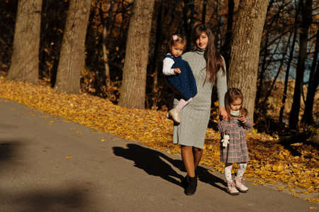 Mother with two daughters at autumn park.の写真素材