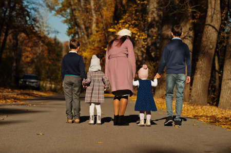 Back of mother with four kids on autumn park.の写真素材
