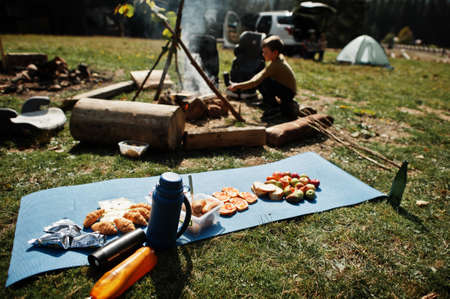 Family bonfire in mountain. Autumn hike and camp weather. Warming and cooking near flame together.
