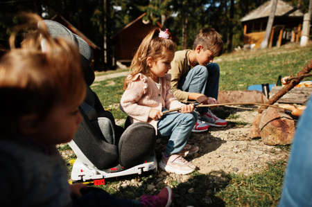 Family bonfire in mountain. Frying sausages. Mother with four kids camping. Autumn hike and camp...