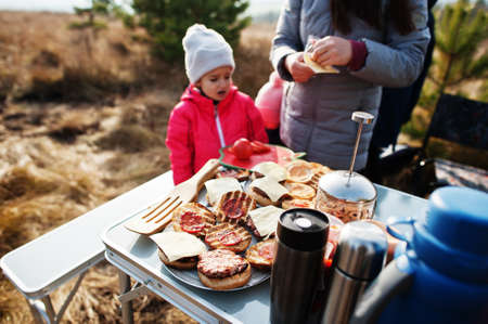 Family barbecuing on a deck in the pine forest. Bbq day with grill.の写真素材