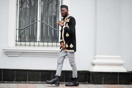 Mega stylish african man in traditional jacket pose. Fashionable black guy in hat and sunglasses...