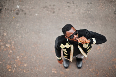 Mega stylish african man in traditional jacket pose. Fashionable black guy in sunglasses with cigar.の写真素材