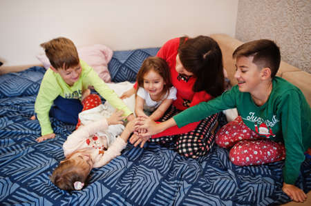 Happy big family is having fun together in bedroom. Large family morning concept. Mother with four kids wear pajamas in bed at home.の写真素材