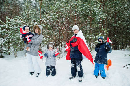 Mother with kids holding flag of Canada on winter landscape.の写真素材
