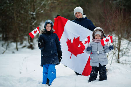 Childrens holding flag of Canada on winter landscape.の写真素材