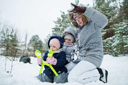 Mother with two baby girl daughters in winter nature. Outdoors in snow.の写真素材