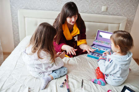 Mother and daughters doing manicures on the bed in the bedroom.の写真素材