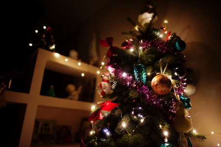 Christmas tree with shining garlands on evening home.