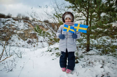 Scandinavian baby girl with Sweden flag in winter swedish landscape.の写真素材