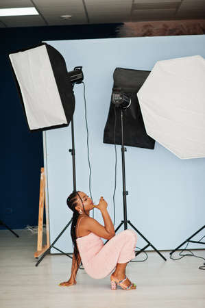 Fashionable photo of young beautiful romantic african american woman with glass of wine, wearing pink dress. studio shoot.の写真素材