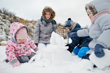 Family plays in winter outdoor, mother and children having fun.
