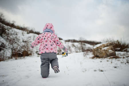 Two baby girls enjoy a sleigh ride. child sledding. Kid riding a sledge on winter.