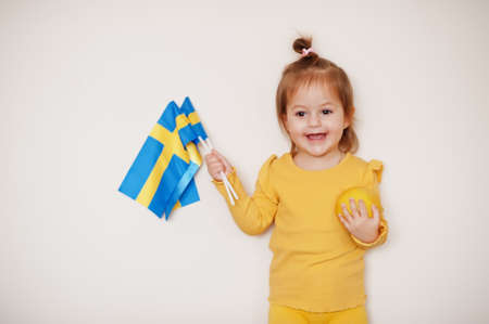 Baby girl in yellow with lemon and Sweden flag, isolated background.の写真素材