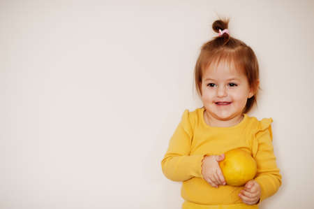 Baby girl in yellow with lemon, isolated background.の写真素材