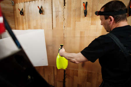 Car service worker put anti gravel film on a red car body at the detailing vehicle workshop. Car protection with special films.の写真素材