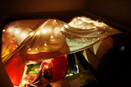 Playing kids in tent at night home. Hygge mood.の写真素材