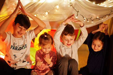 Playing kids in tent at night home. Hygge mood.の写真素材