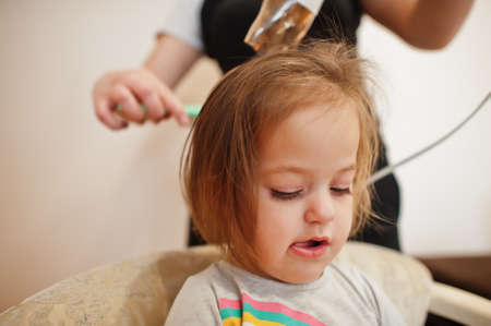 Mom with baby dauhter making everyday routine together. Mother is brushing and drying child hair after shower.の写真素材