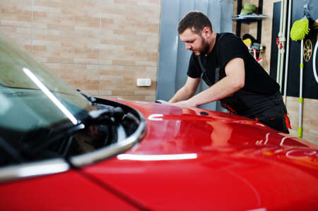 Man worker washing red car in detailing garage.の写真素材