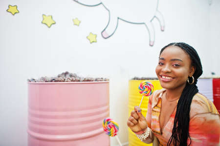 African american millennial lady at candy shop with lolipops.の写真素材