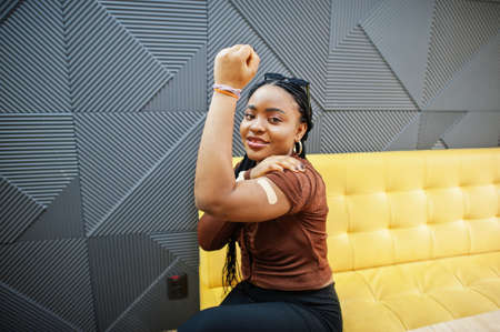 stay safe! Black woman showing vaccinated arm after vaccine injection.