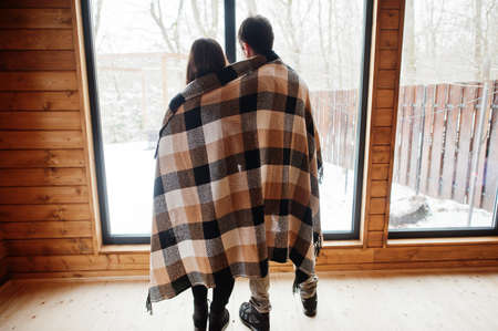Couple covered blanket in modern wooden house spending time together in warm and love.の写真素材
