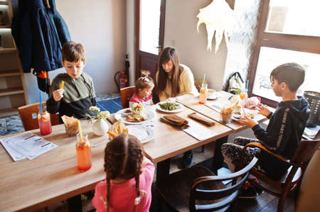 Mother with four kids spending time in cafe. Family lunch in the cafeteria.の写真素材