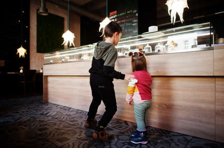 Brother with sister in cafe choose a dessert from shop window.の写真素材