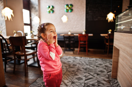 Young girl wth shocked reaction in cafe choose a dessert from shop window.の写真素材