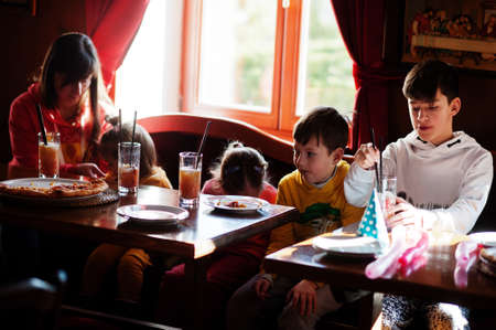 Children on birthdays sitting at the table and eating pizza.の写真素材