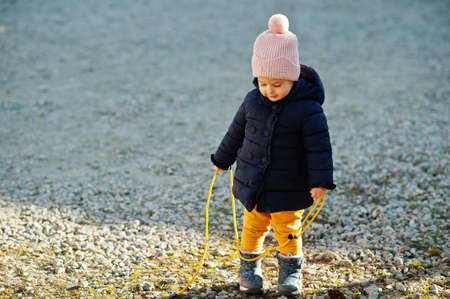 Little baby girl in the sun hold rope jump.の写真素材