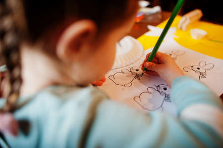 Preparing to Easter concept. Little girl drawing bunny.
