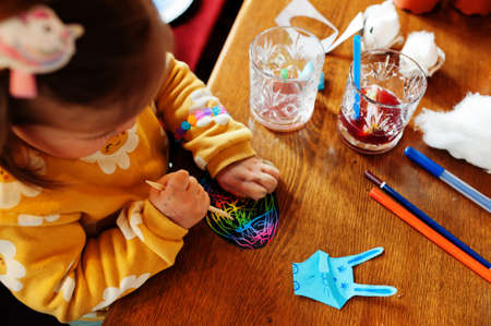 Preparing to Easter concept. Hands of baby girl drawing on egg.の写真素材