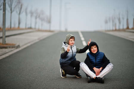 Brothers in hoodie sitting at the center of the road.の写真素材