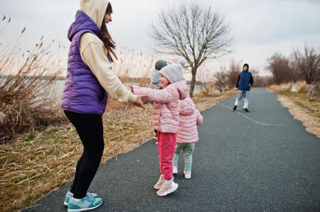 Mother with kids jump and having fun on the path by the lake.の写真素材