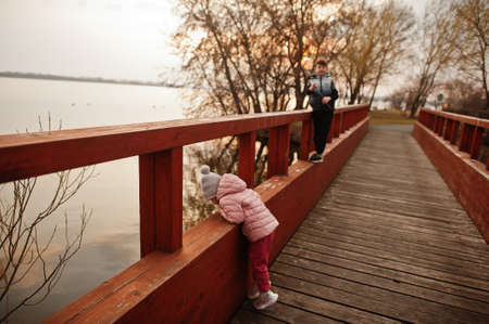 Brother with sister in bridge of island at lake.の写真素材