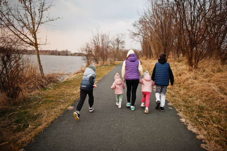 Back of mother walking with kids on the path by the lake.