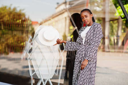Beautiful african american woman natural makeup wear fashion clothes casual black and white dress code office style total blouse and pants suit and hat.の写真素材