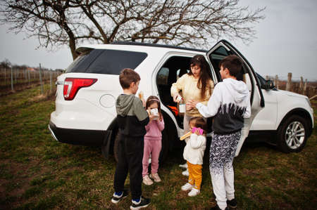 Mother with kids drink tea outdoor near white suv car.の写真素材