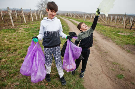 Brothers with trash bag collecting garbage while cleaning in the vineyards . Environmental conservation and ecology, recycling.の写真素材