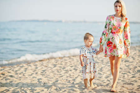 Mother and beautiful daughter having fun on the beach. Portrait of happy woman with cute little girl on vacation.の写真素材