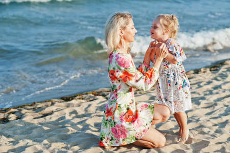 Mother and beautiful daughter having fun on the beach. Portrait of happy woman with cute little girl on vacation.の写真素材