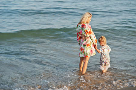 Mother and beautiful daughter having fun on the beach. Portrait of happy woman with cute little girl on vacation.の写真素材