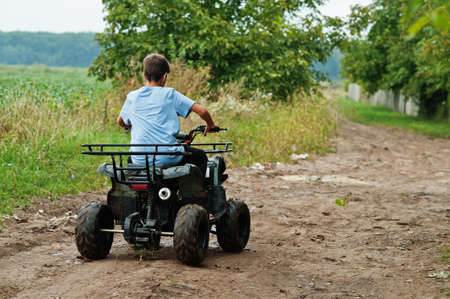 Boy drive four wheeler ATV quad bike.