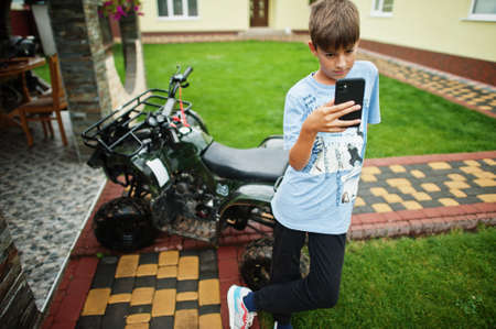 Boy in four wheeler ATV quad bike with mobile phone.の写真素材