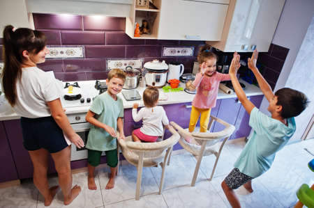 Mother with kids cooking at kitchen, happy children's moments. Give high five each other.の写真素材