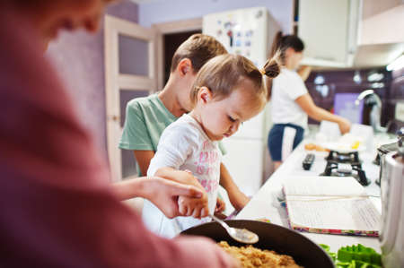 Mother with kids cooking at kitchen, happy children's moments.の写真素材