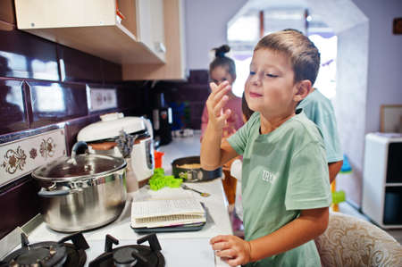 Kids cooking at kitchen, happy children's moments. Delicious lick your fingers!の写真素材
